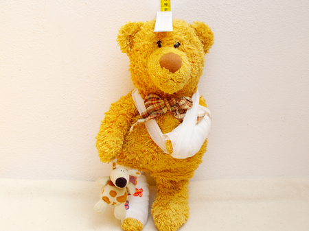 sick teddy with plaster and bandage on the arm is measuredの写真素材