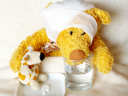 sick teddy with head band takes his medicineの写真素材