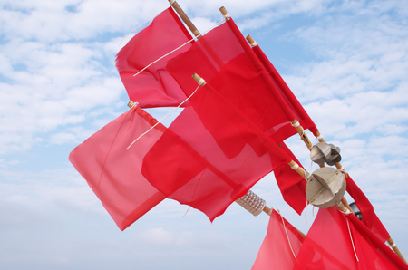 red fisherman banners in front of blue skyの写真素材