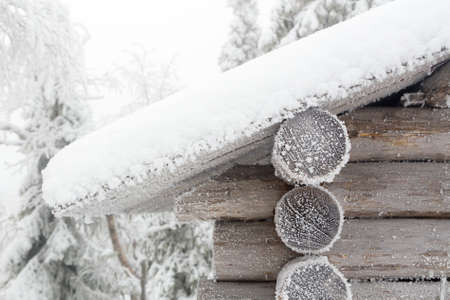 The wall and the edge of the roof of the hut covered with frost and snow on the background of a winter forest.  Finnish Lapland.の写真素材