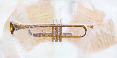 Brass trumpet and sheet music frozen into the ice.の写真素材