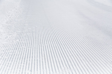 Prepared snowcat trail on a background of mountains.