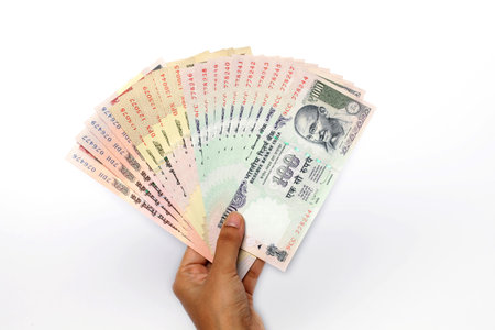 Hand with Indian rupee notes on white background
