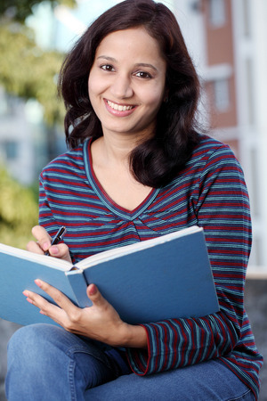 Smiling Indian female student holding books の写真素材