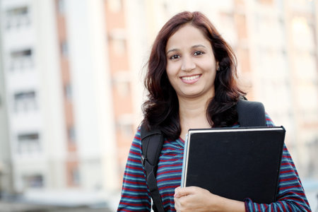 Smiling Indian female student holding books の写真素材