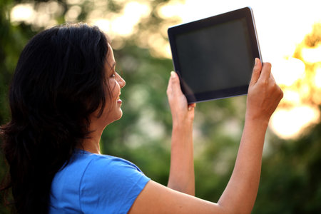 Young woman taking picture from tablet computer at outdoors