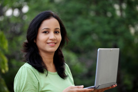Happy young female student working with tablet computer at campusの写真素材
