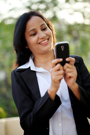 Happy young business woman text messaging at outdoorsの写真素材