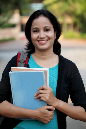 Happy young female student at college campus and carrying books の写真素材