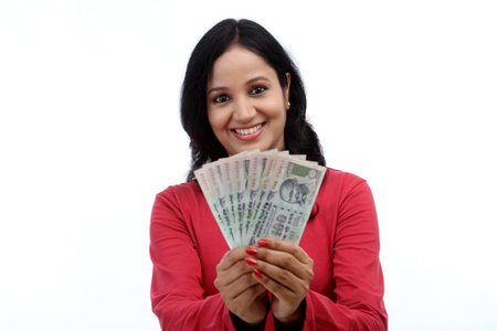 Young woman holding Indian rupee notes against white background