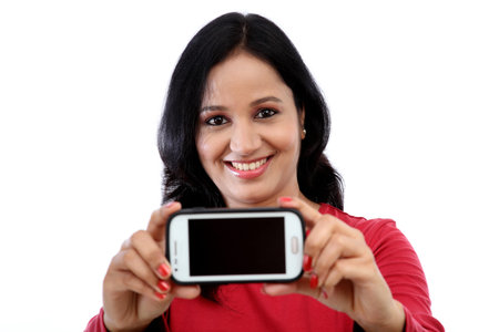 Beautiful young woman holding mobile phone against white background