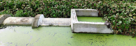 Concrete circular run-off pipe discharging water. sewage pipe polluting the riverの写真素材