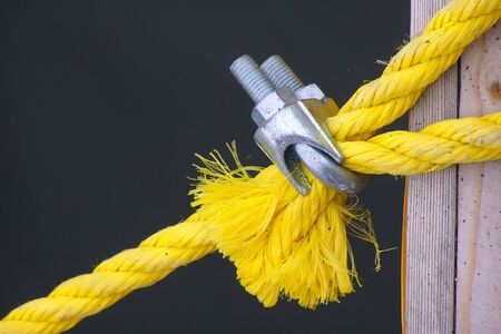 a yellow rope for a tie-down is clamped by metallic fasteningの写真素材