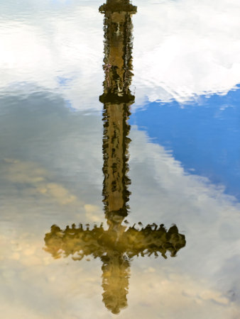 cross and sky reflection in water