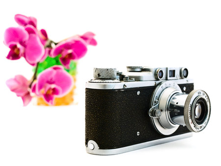 old photocamera and pink orchid over the white background