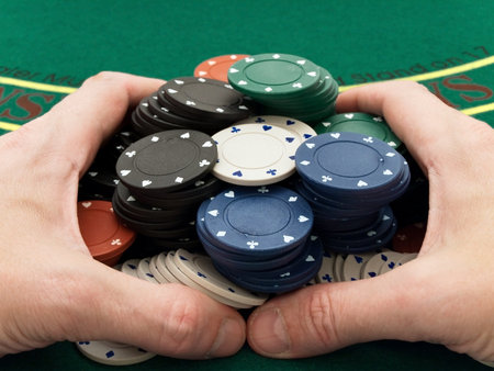 hands holding the stacks of playing chips at the green table into the casino