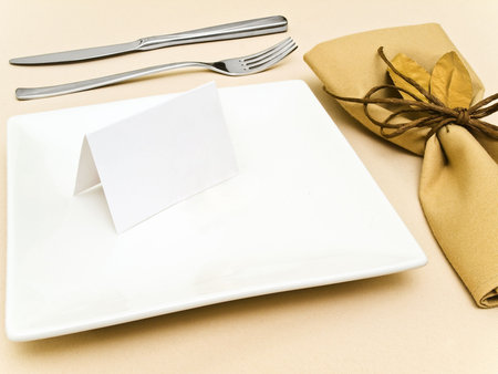 decorated table serving with golden bay leaves in serviette and cord near plate, knife and fork at...