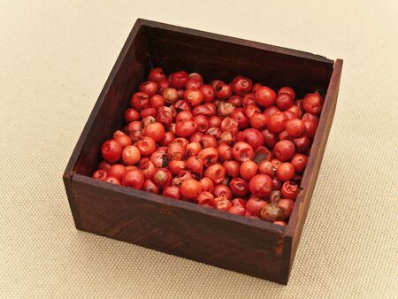 red pepper seeds in wooden box at beige textileの写真素材