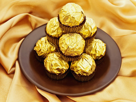 confection heap on the saucer over golden textile background の写真素材