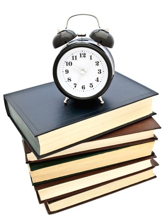 "Time to learning!" theme with alarm clock at stack of books over white の写真素材