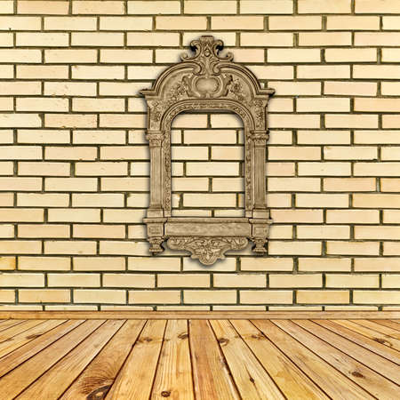 antique decorated frame at beige brick wall under wooden floorの写真素材