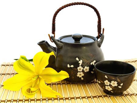 tea set with lily flower at mat over the white background の写真素材