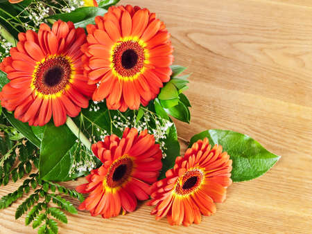 bouquet of gerberas with green leaves over wooden backgroundの写真素材