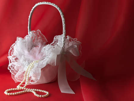 bridal white flower basket with pearl beads over red draperyの写真素材