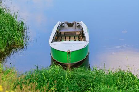 Old metal rowboat moored on the lake の写真素材