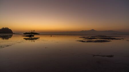 Magical vibrant gradual sunset scene with volcano or sunrise water like a glass in Sumbawa island, Indonesiaの写真素材
