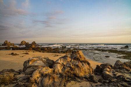Nice lava rock formations at undiscovered beachlighted in golden evening glow found in Sawarna,...