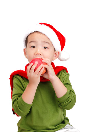 Boy wearing Christmas costume eating apple isolated on white backgroundの写真素材