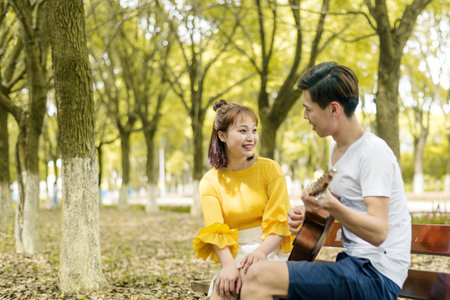 College students on campus, playing guitar, listening to musicの写真素材