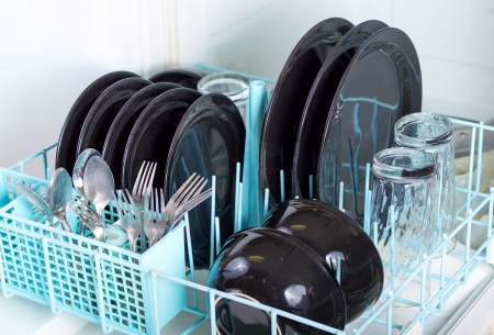 Dishwasher rack loaded with clean plates, glasses and silverware.の写真素材