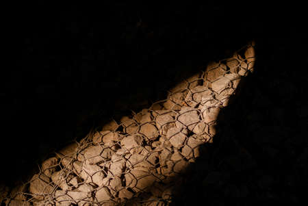 A beam of light illuminates the stones under the barsの写真素材
