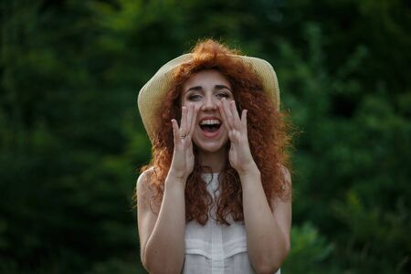 Woman in straw hat calling somebodyの写真素材
