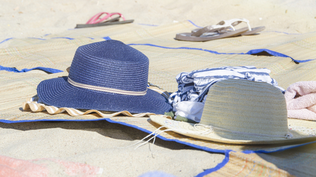 two womens straw hats on the beach for sun protection in the tropical heatの写真素材