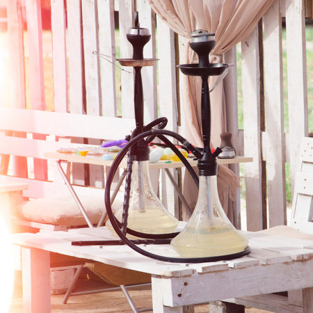 two of hookahs on wooden table outdoors