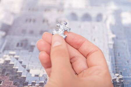 woman hands putting pieces of semi-assembled puzzleの写真素材