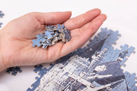 woman hands putting pieces of semi-assembled puzzleの写真素材