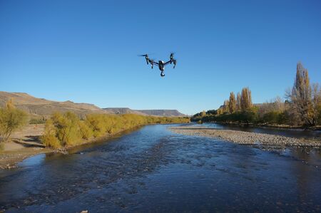 Inspire quadcopter drone flying over river. (back view)の写真素材