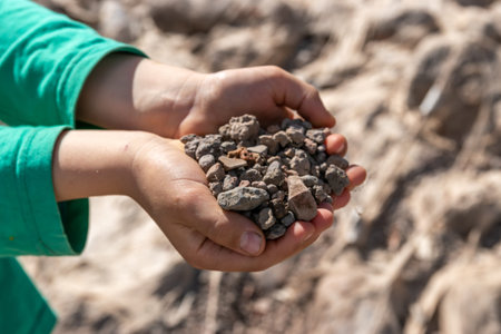 Child holding small colorful stones in little hands. Concept of game money, valuable resource