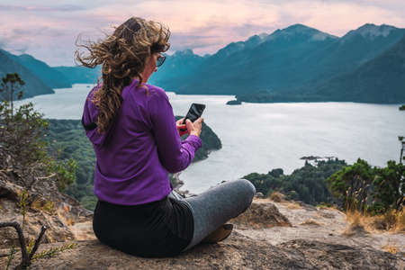 latin woman with cell phone in mountainous landscapeの写真素材
