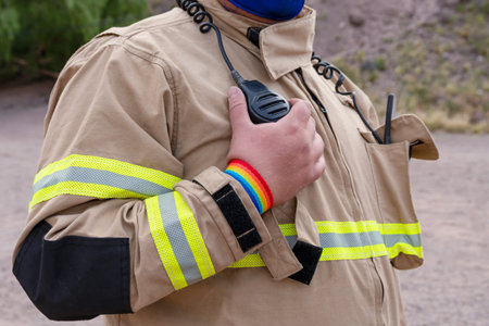 firefighter speaking by handy, with LGBT bracelet.