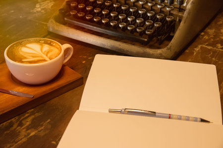 Close up Blank Notebook and vintage typewriter on the wooden table with coffee
