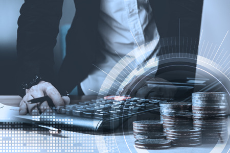 double exposure of businessman working with laptop,smartphone,laptop and row of coins with diagram and digital interface in finance and business conceptの写真素材