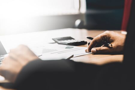 Business man working on his wooden table in the office with calculator,document,smart phone,pen and laptop in business,finance and banking conceptの写真素材