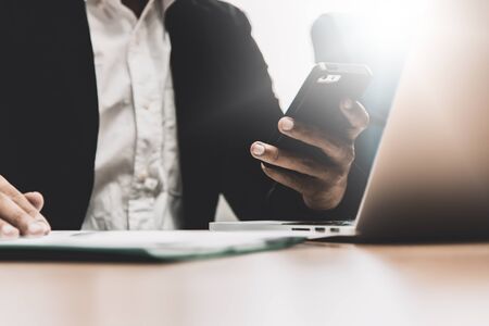 Close up of businessman working in his office with smart phone,doccument and laptop in business conceptの写真素材