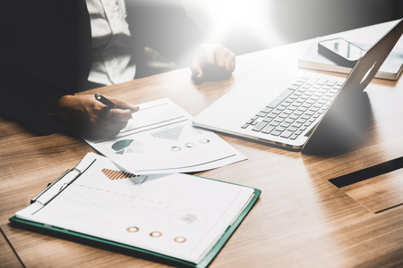 Business man working on his wooden table in the office with calculator,document,smart phone,pen and laptop in business,finance and banking conceptの写真素材