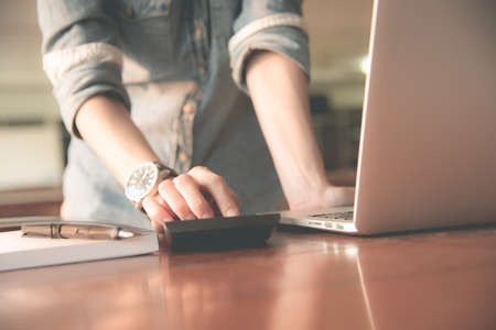 Business women work with calculator and laptop,pen and notebook on the wooden tableの写真素材